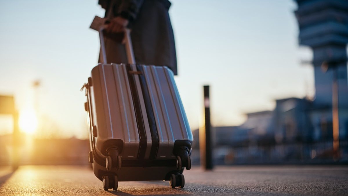 Călător cu valiză sosind la aeroport la răsăritul soarelui