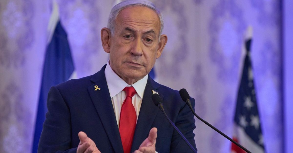 Prim-ministrul israelian Benjamin Netanyahu, în sacou negru, camasa alba si cravata rosie, tine maine in fata, impreunate, si palmele deschise, in timp ce vorbește la o conferință de la Ierusalim, duminică, 27 iulie 2025.