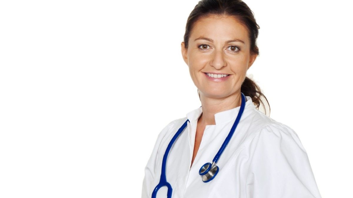 Medic tanar, femeie, imbracata in halat alb cu stetoscop la gat, zambeste.Obligatia medicilor de-a ramane in tara.FEPAM. Foto: Hepta