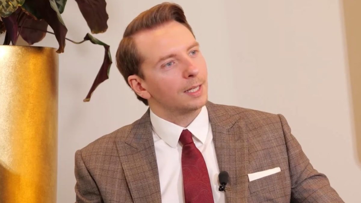 Paul Olteanu, îmbrăcat cu un costum de culoare maro, cămașă albă și cravată roșie, la interviurile Imobiliare.ro