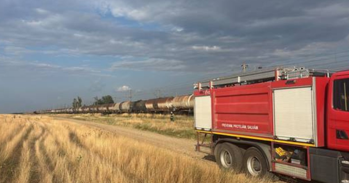 O mașină de pompieri care stă în apropierea unui tren de marfă care transportă motorină