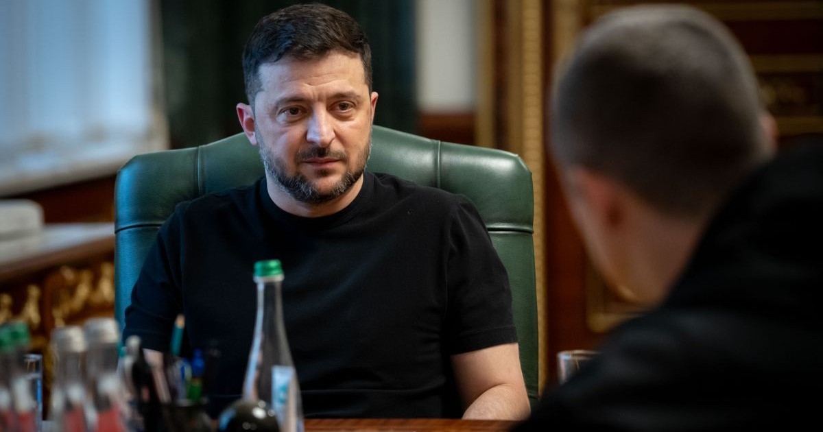 Președintele Volodimir Zelenski, îmbrăcat în tricou negru, este la o întâlnire cu Mykhailo Fedorov, prim-viceprim-ministrul Ucrainei, și stă pe un scaun cu spătar verde, la birou.
