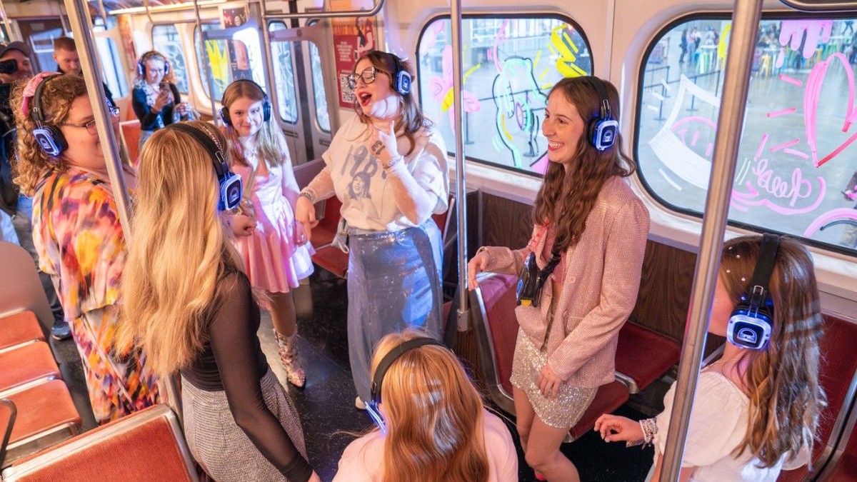 Mai multe adolescente ascultă muzică în căști în timpul deplasării cu metroul