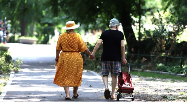 Doi pensionari imbracati frumos merg pe strada tinându se de mana