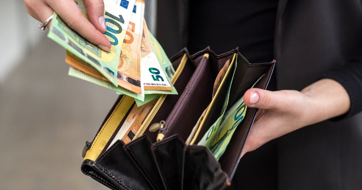 O femeie care scoate bancnote euro dintr-un portofel.