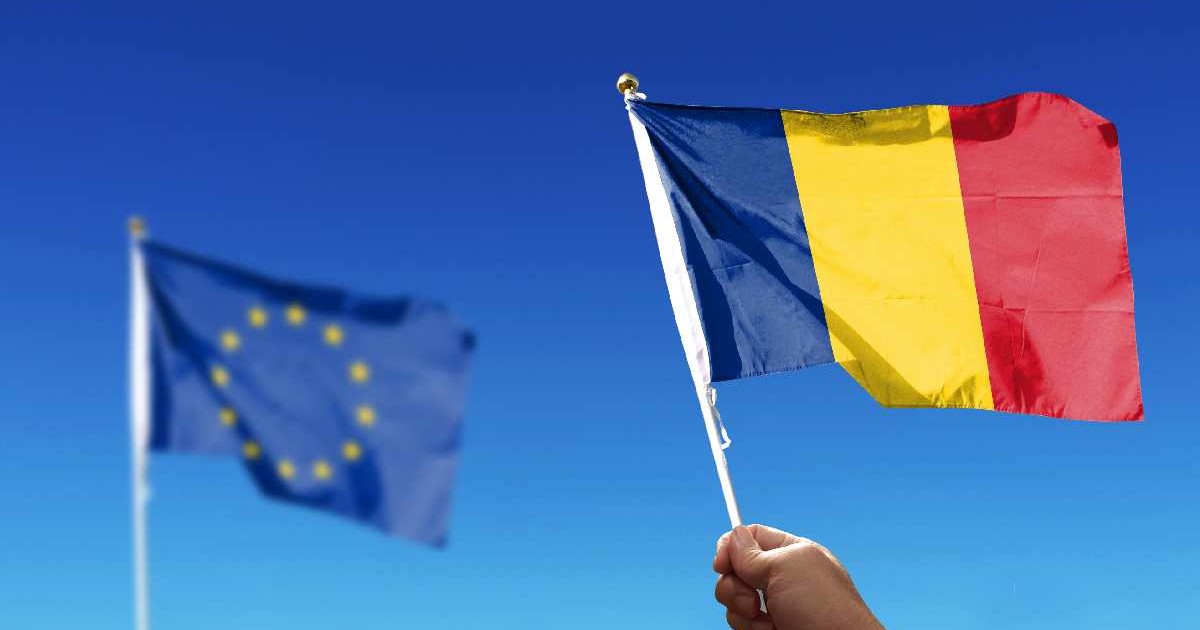 Steagul României, țară membră a UE, flutură pe un cer senin, lângă cel al UE
