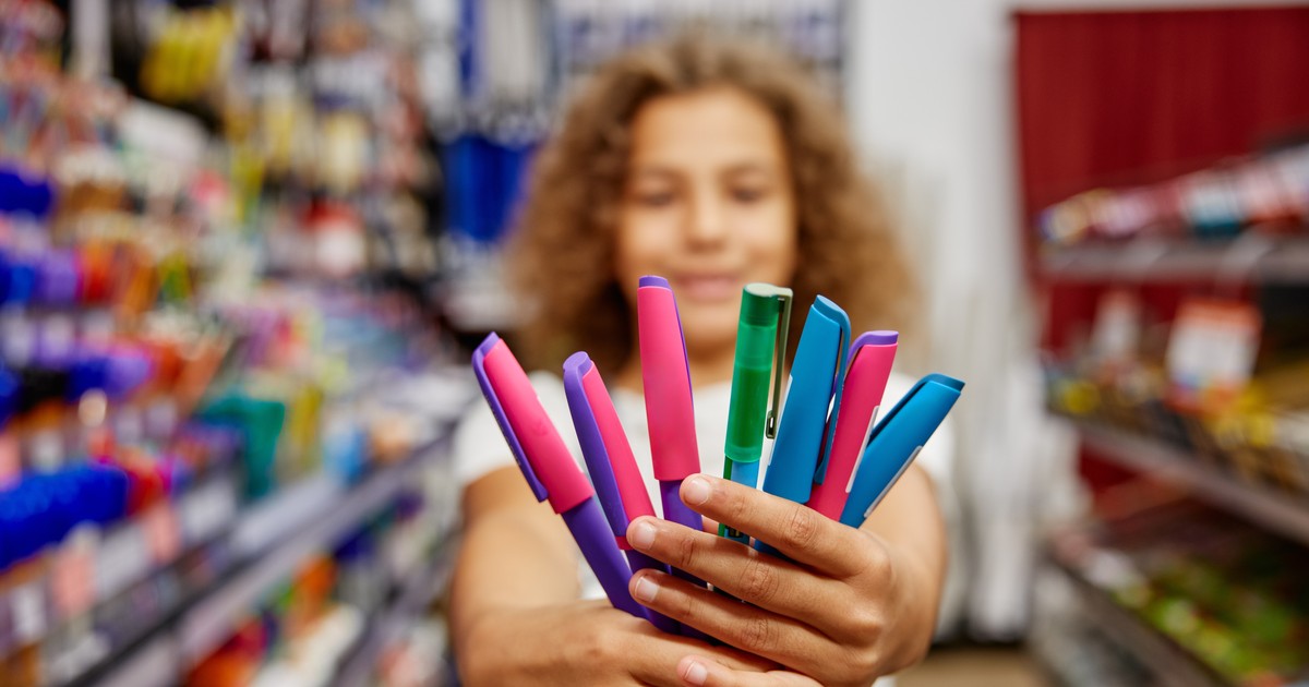 Copil care ține în mână niște creioane colorate