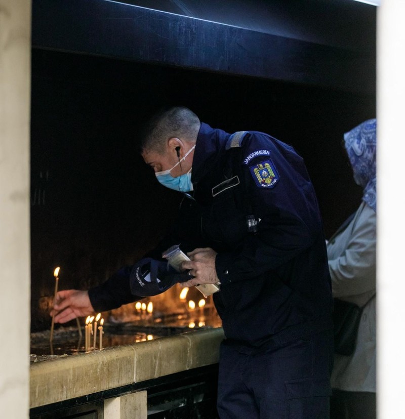 Jandarm aprinzând lumânări în numele celor care nu au ajuns la pelerinaj