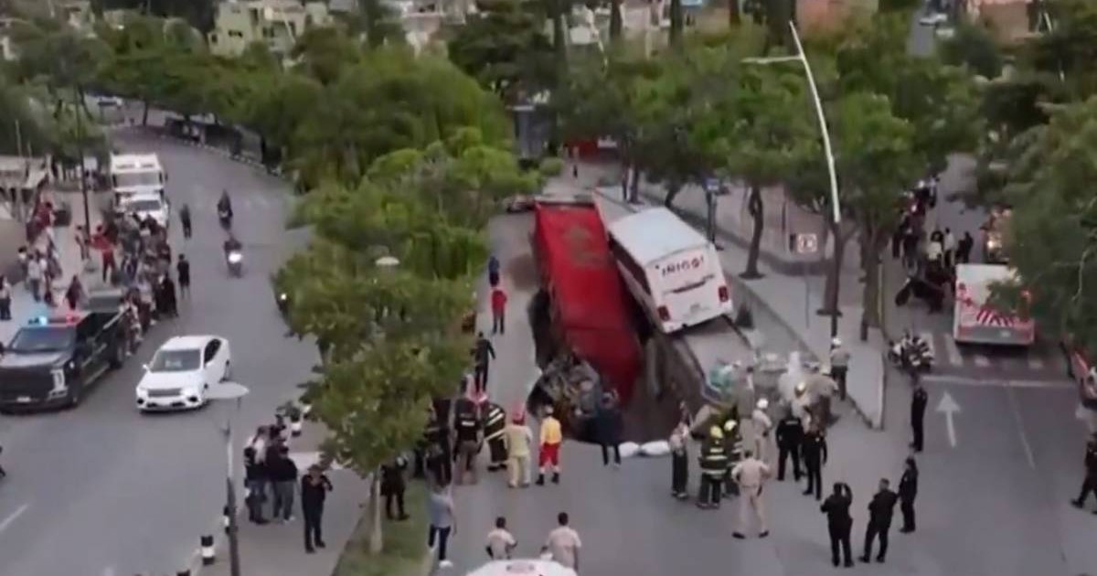 Imagine cu autocarul și camionul în groapa uriașă din Mexic. În jur se află mai mulți oameni