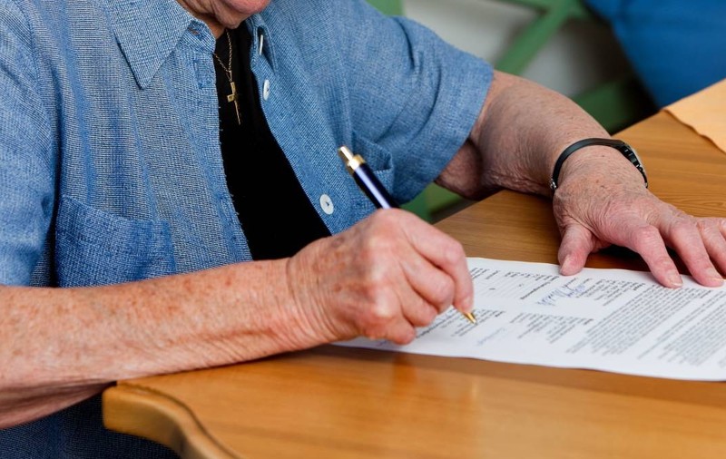 O  femeie pensionară semnează un contract. Poză cu caracter ilustrativ. Sursă foto: Getty Images
