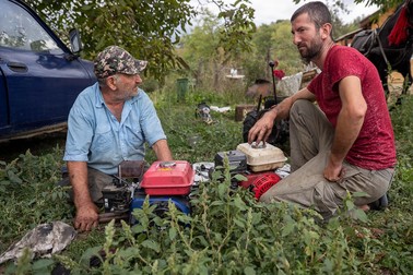 Gheorghe îl ajută pe vecinul său Ionuț să repare o motocoasă. Sursa foto: Eli Driu