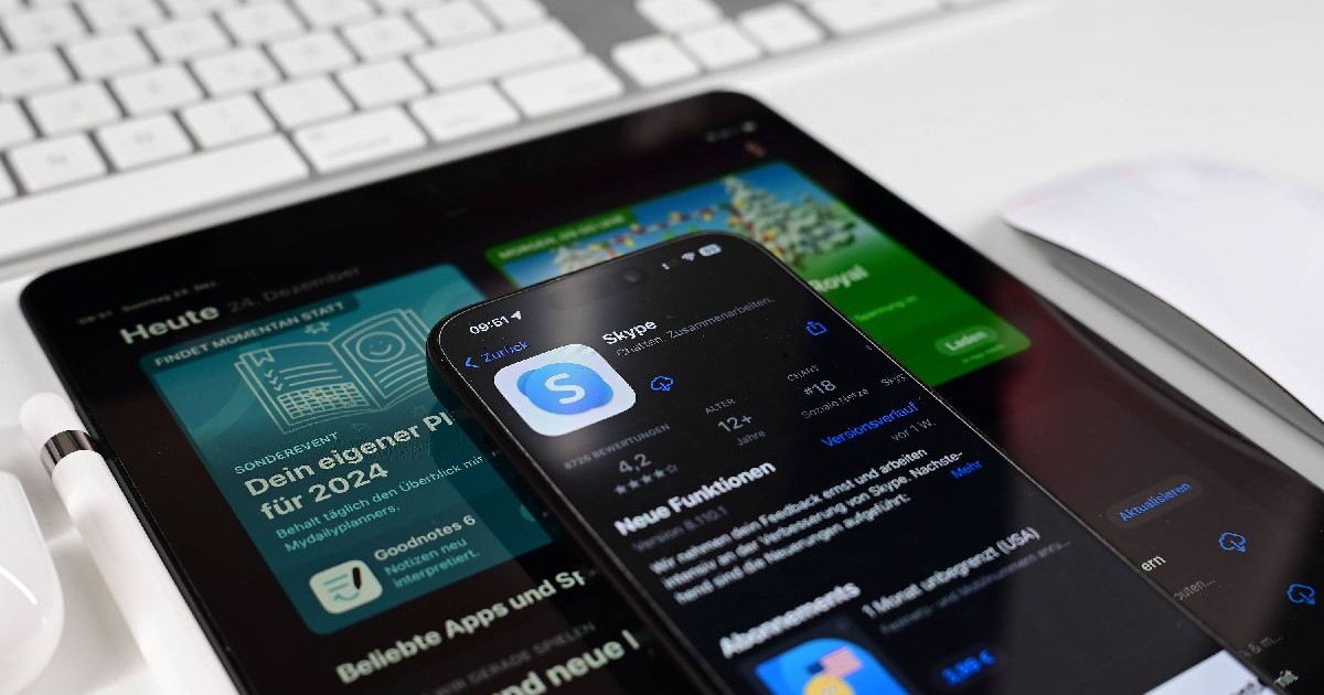 Aplicația Microsoft Skype, deschisă pe un telefon, care este așezat la rândul lui deasupra unei tablete pe care sunt deschise știri.