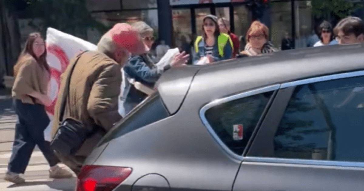 Captura video o masina gri loveste un barbat cu geaca crem, sapca rosie pe cap, mai multi oameni se uita speriati