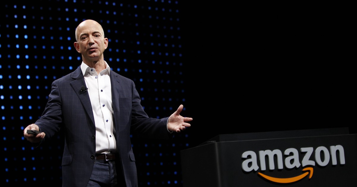 Jeff Bezos și Michael Bloomberg, printre cei mai mari donatori americani din 2020. Jeff Bezos în costum cu logo-ul Amazon în spate