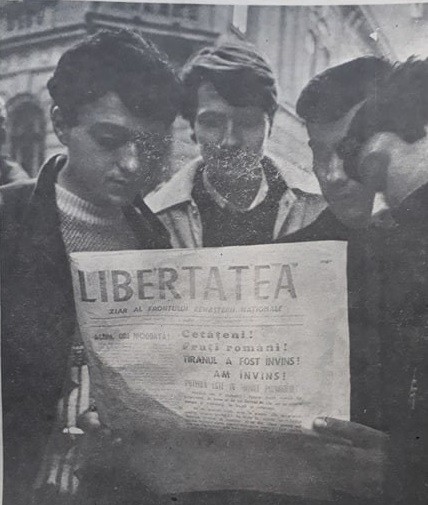 Câțiva tineri citind primul număr al ziarului Libertatea. Fotografia a fost făcută chiar pe 22 decembrie 1989, de fotoreporterul ziarului Gabriel Miron