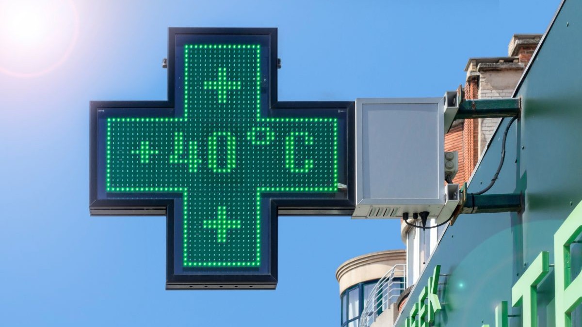 Termometru montat pe fațada unei farmacii care indică o temperatură de 40 de grade Celsius, cu cerul albastru pe fundal