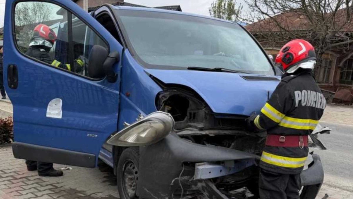 Pompieri care se află lângă un microbuz albastru, în urma unui accident.