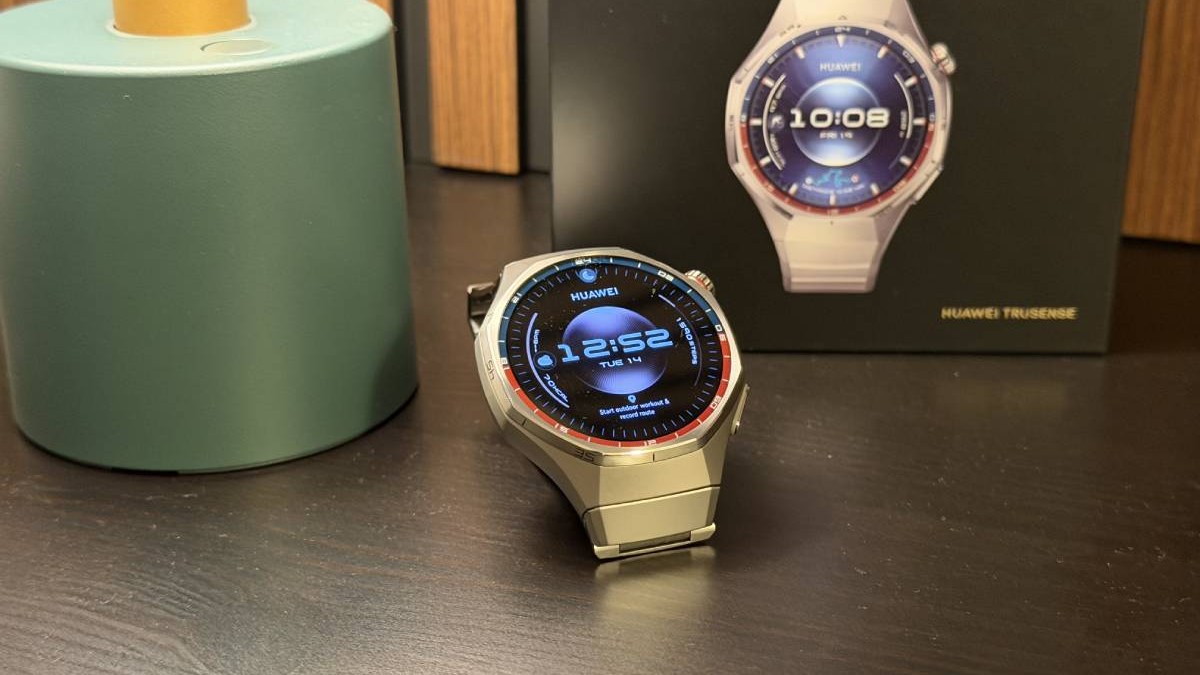 Un smartwatch Huawei GT 6 Pro cu curea de metal, pe un fundal de lemn, cu cutia sa de culoare neagră în spate.