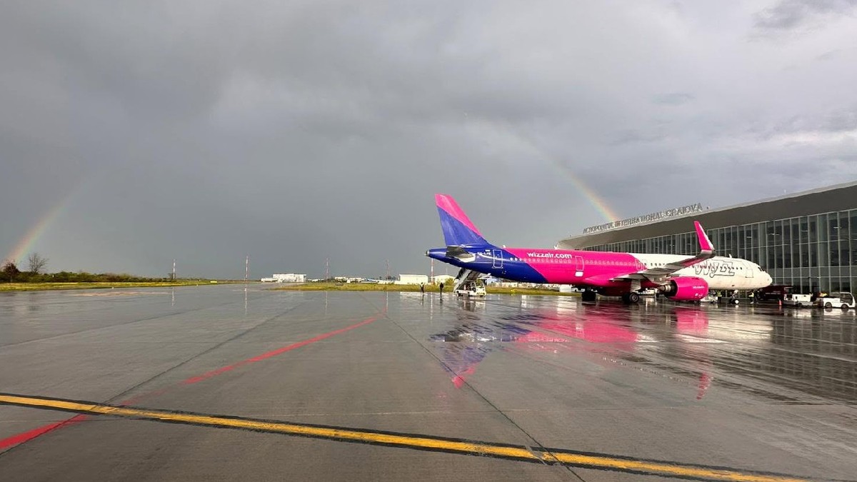 aeronavă wizz air pe aeroportul din Craiova, într-o zi înnorată, se vede curcubeul