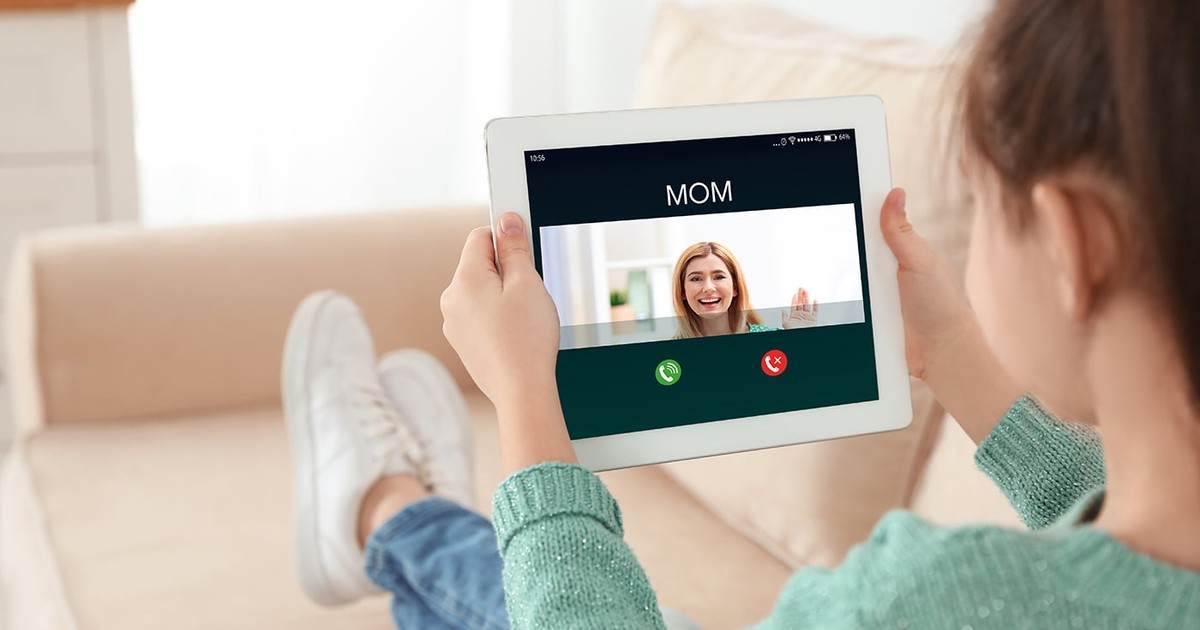 Vedere de aproape a unei fetițe care folosește o tabletă pentru a conversa cu mama prin chat video acasă
