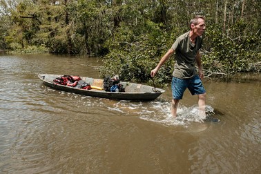 Un bărbat trage după el o barcă în care se află unelte, pe o stradă inundată din Baratania, Louisiana Foto: EPA