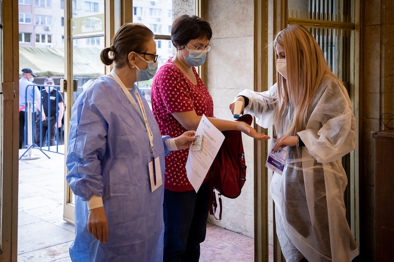 Patricia, studentă în anul II la Medicină, le ia temperatura oamenilor veniți la vaccinare