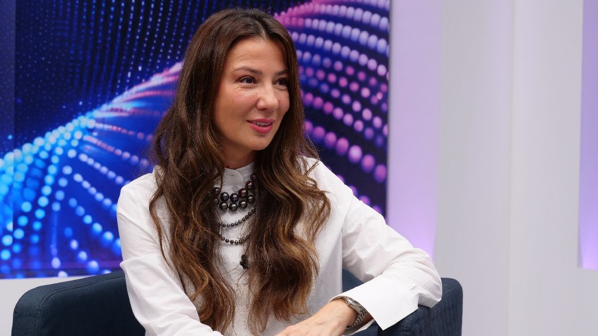 Mirela Bucovicean, intr-o bluza alba, pe un fotoliu in studioul Libertatea. poarta un sirag de margele la gat sia re parul lung