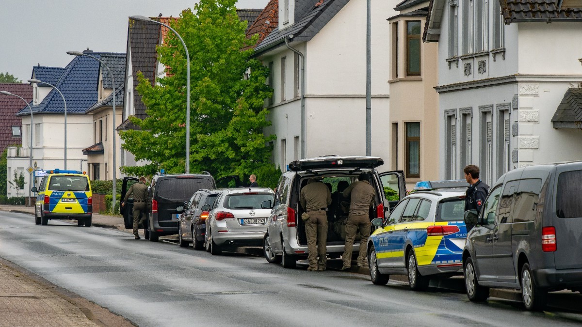 Mașini de poliție parcate în fața unei case din Germania, în timpul unei interventii