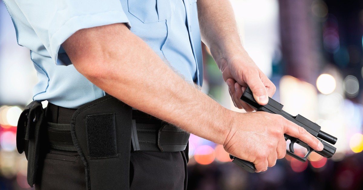Imagine cu un polițist care ține în mâini un pistol