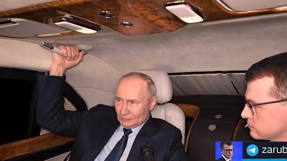 Vladimir Putin, pe bancheta din spate a unei mașini, vorbind cu un reporter care ține un microfon