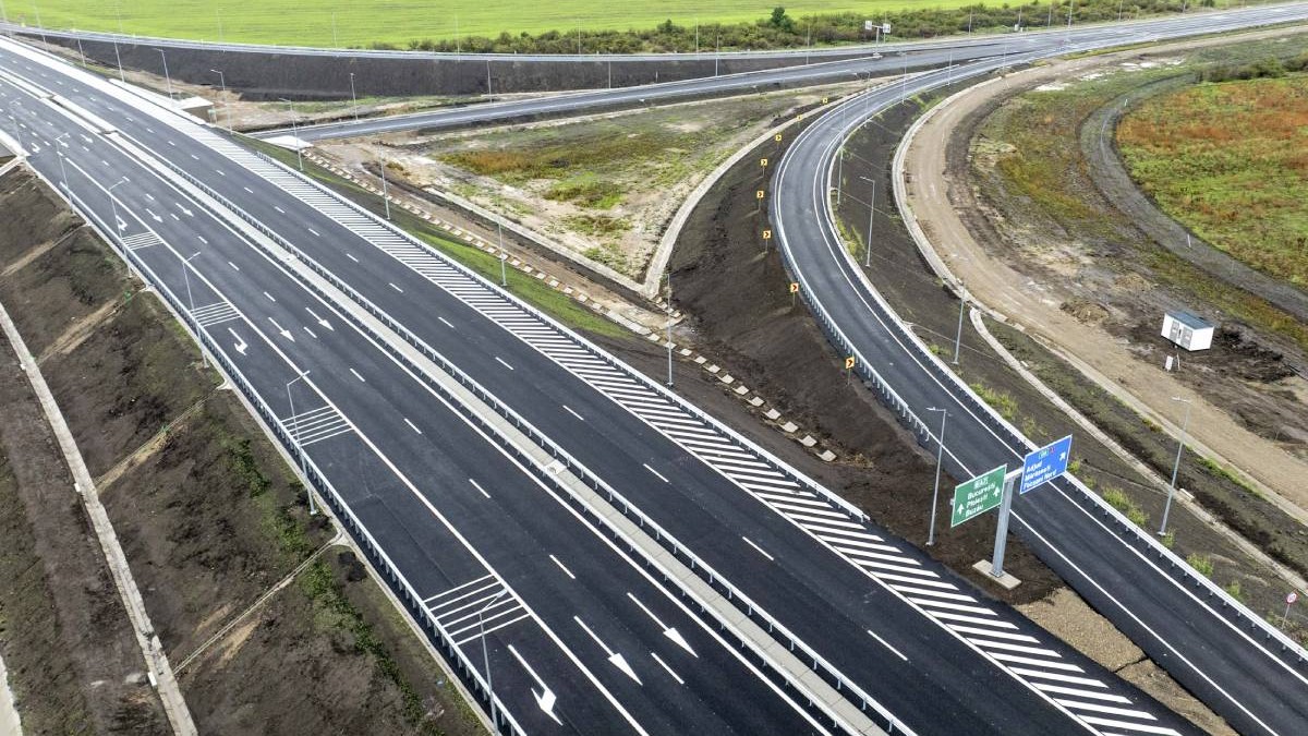 autostradă nou construită cu mai multe benzi pe fiecare sens de circulație și marcaje rutiere. nod rutier cu bretele de acces și ieșire. indicatoare rutiere pentru direcțiile de mers și parapete de siguranță