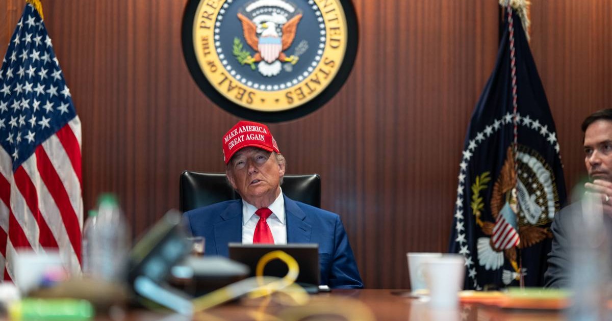 Donald Trump surprins în capul mesei, în Situation Room, stând serios și purtând o șapcă roșie cu sloganul „Make America Great Again”. Fotografia a fost realizată pe 21 iunie 2025