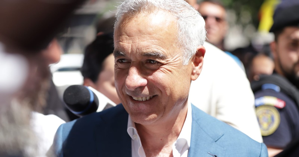 Călin Georgescu între susținători. in costum albastru si camasa alba, zambeste larg