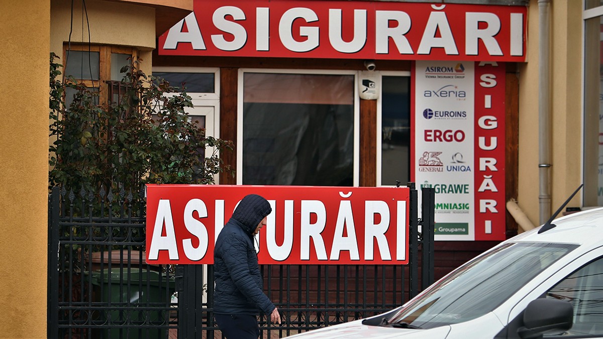 Oameni trecând prin fața unui magazin pe care scrie mare Asigurări