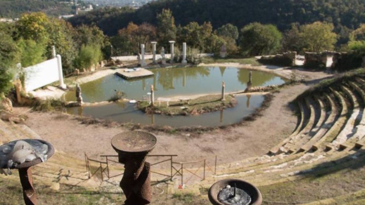 În imagine se vede o construcție care seamănă cu un amfiteatru antic, în mijlocul căreia se află un iaz