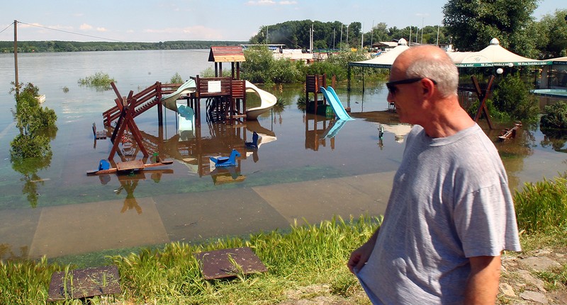 Un bărbat trece pe lângă un parc inundat de-a lungul fluviului Dunărea în Belgrad, Serbia | Foto EPA