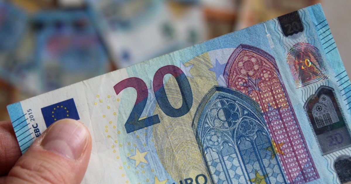 Un bărbat șine în mână o bancnotă de 20 de euro
