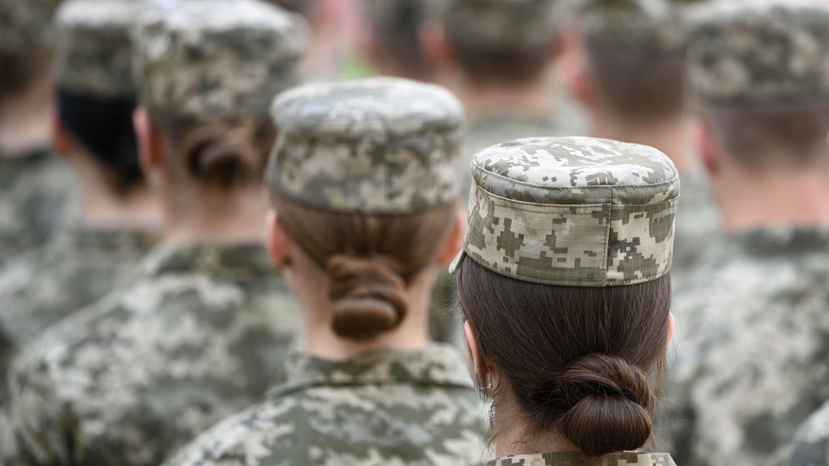 Imagine cu patru femei care stau una în spatele celeilalte. Acestea poartă uniforme militare și au părul strâns în coc