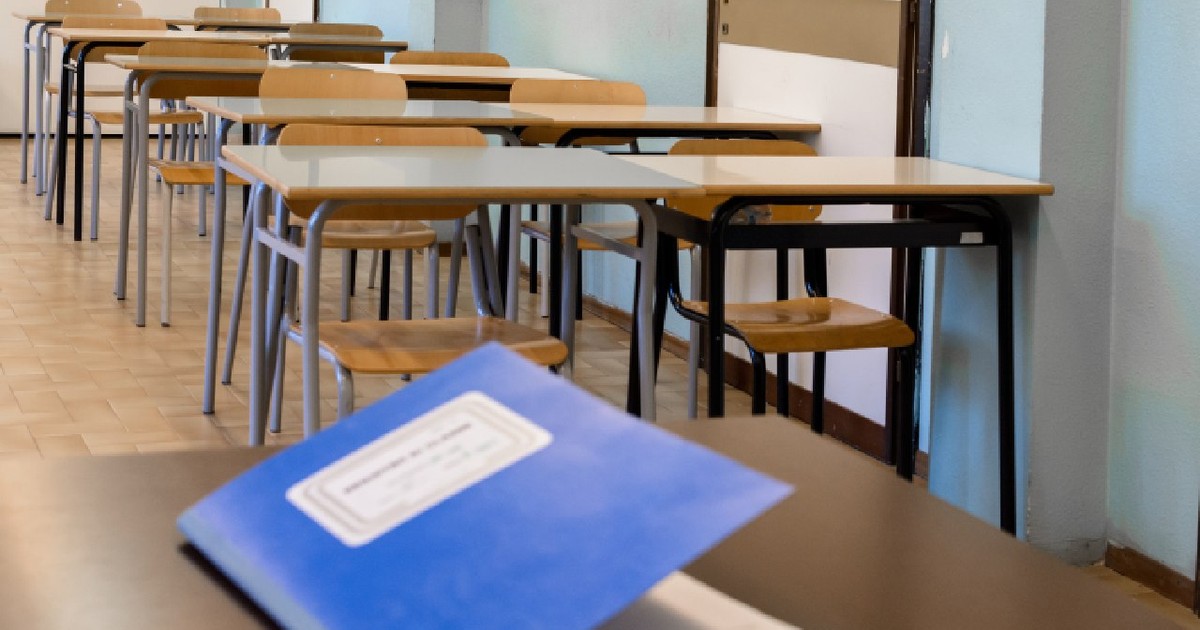 Catalogul clasei închis pe catedră, într-o clasă de liceu, în fundal băncile elevilor.