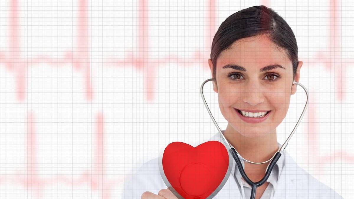 O doamnă doctor ține în mână o inimă roșie și zâmbește, în urechi are brațele unui stetoscop și e îmbrăcată cu un halat alb