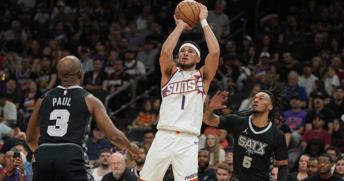 jucataorul de baschet Devin Booker, in echipament alb, arunca la cos