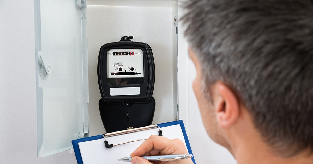 Un bărbat citește contorul de energie electrică și scrie indexul pe o hârtie