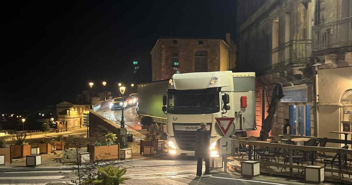 Scena nocturnă pe stradă, cu un camion alb mare care blochează drumul