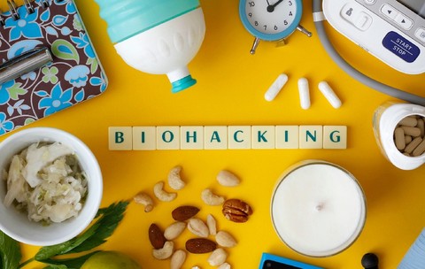 textul „Biohacking” pe fundal galben, înconjurat de diverse obiecte ce fac parte dintr-un stil de viață sănătos 