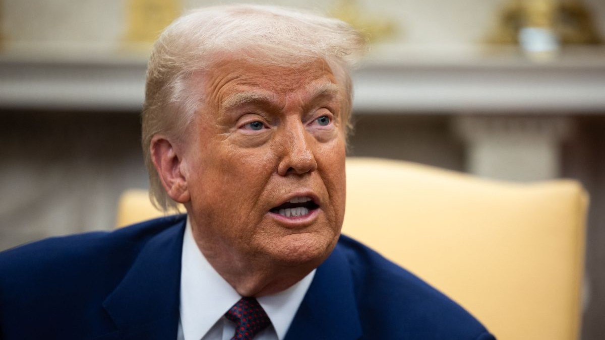 Donald Trump, președintele Statelor Unite ale Americii, îmbrăcat într-un costum de culoare albastră, cu Biroul Oval pe fundal, în blur