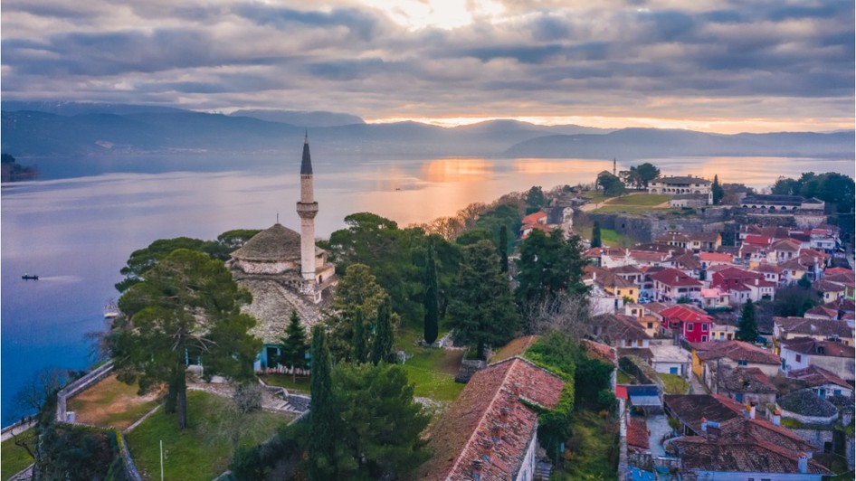 Panoramă pitorească a cetății istorice Ioannina din Grecia, situată pe o peninsulă ce înaintează în lacul Pamvotis, cu moscheea Fethiye și minaretul său evidențiate în prim-plan la apus.   
