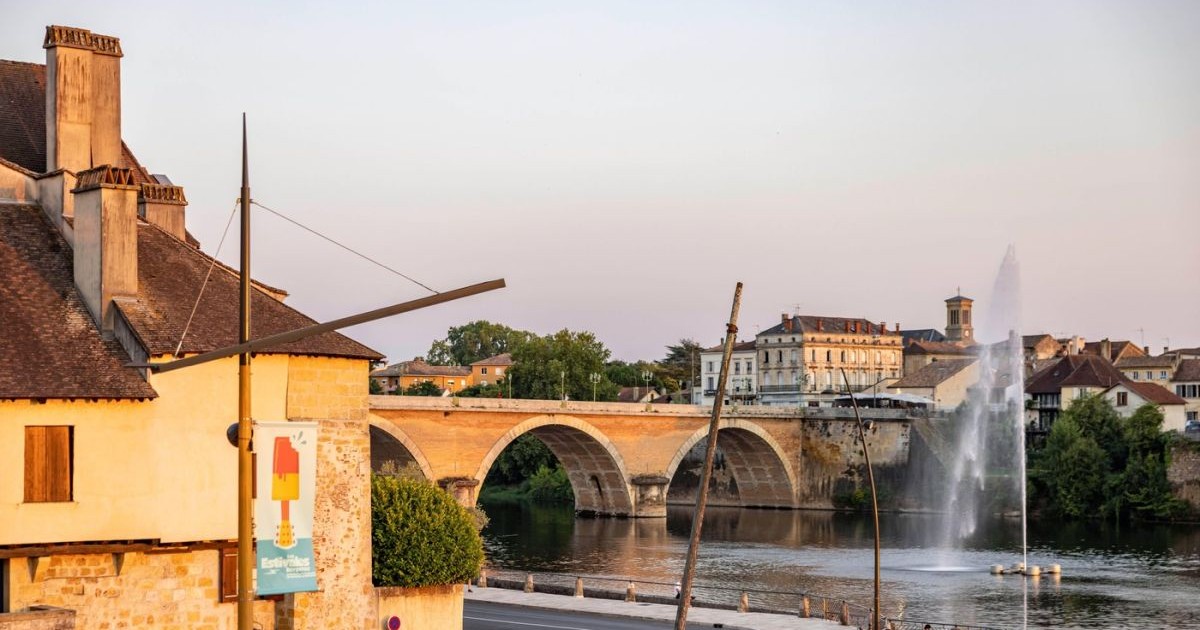 O casă veche și un pod de piatră pe sub care curge o apă în orașul orașul Bergerac, Franța, 21 iulie 2022