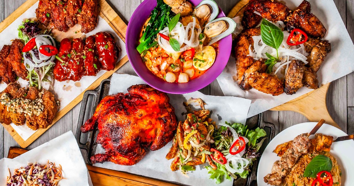 Orez prăjit cu usturoi, frigărui, pui întreg la grătar, peri peri, platou cu aripi prăjite, supă de vită cu tăiței, laksa cu fructe de mare și coaste de porc americane, servite izolat pe o masă de lemn - mâncare din Hong Kong