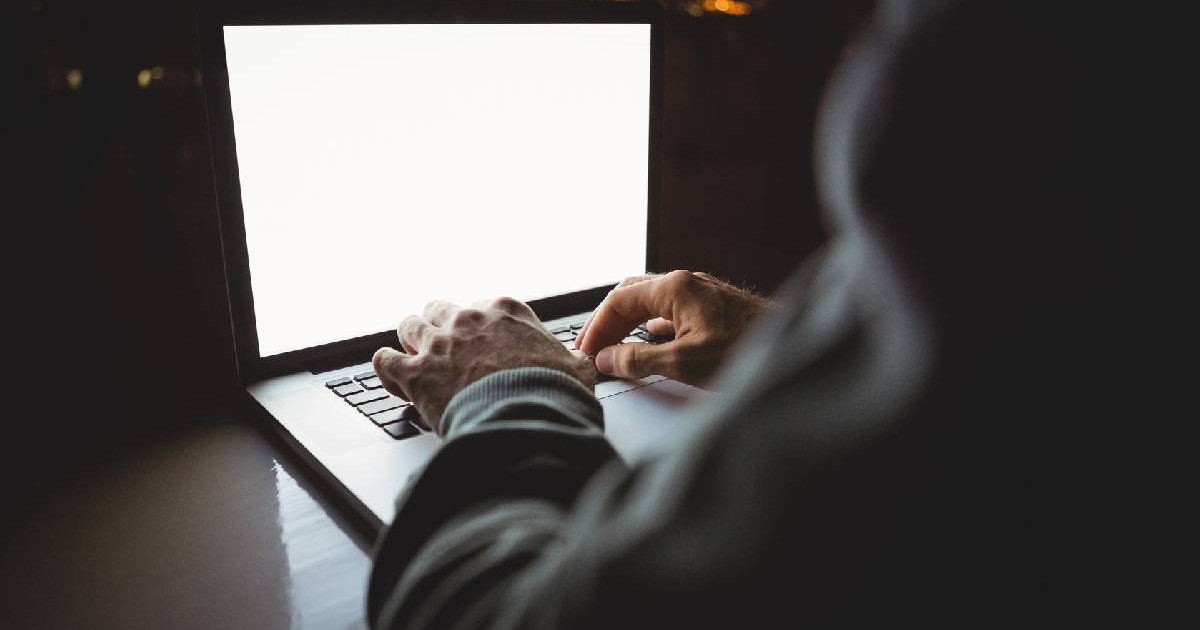 un laptop e deschis și se observă mâinile cuiva care-l manipulează