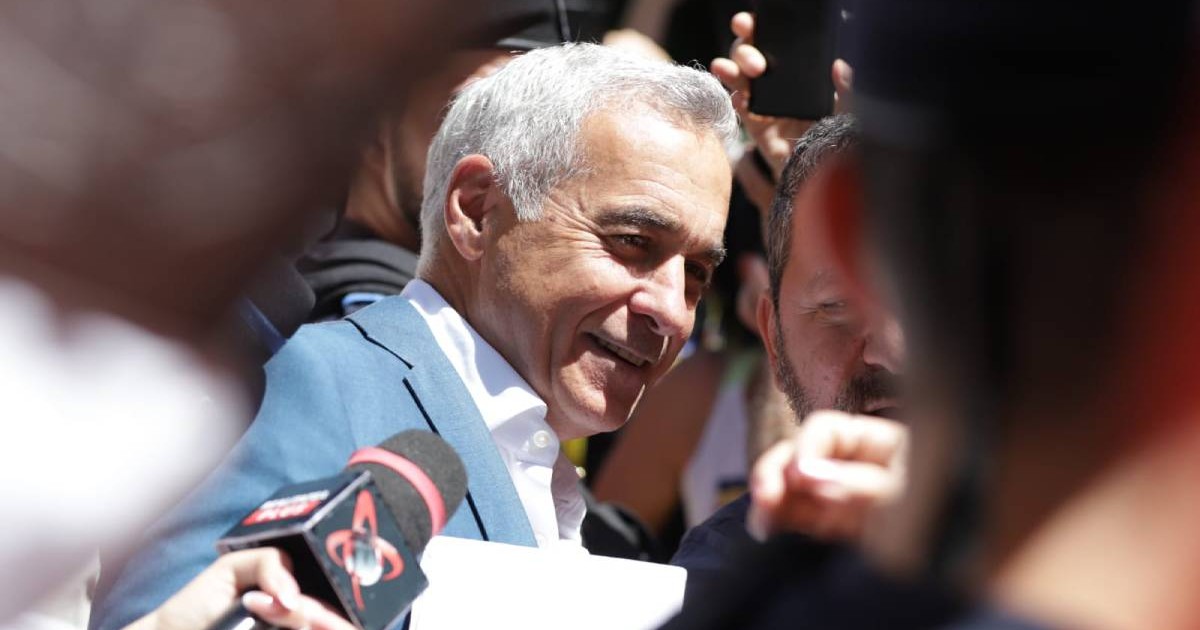 Călin Georgescu în timp ce coboră din mașină în fața Judecătoriei Sectorului 1 din București, âmbește în fața camerei și este înconjurat de manifestanți și susținători